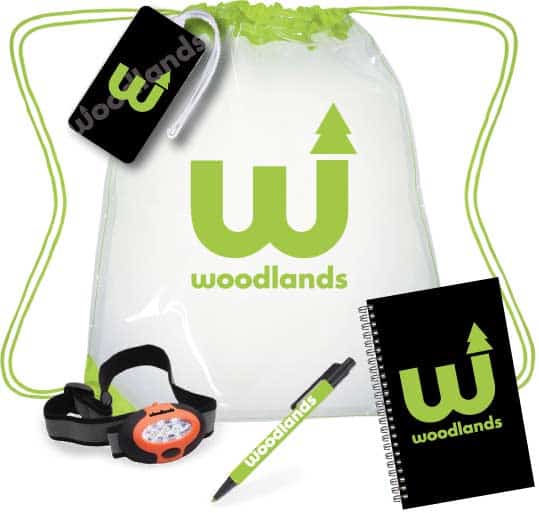 Image of a camper pack for Woodlands Camp. The pack includes a cinch pack, luggage tag, notebook, headlamp, and pen, all branded for Woodlands Camp.